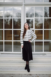 a lady wears a velvet midi skirt with a striped cardigan